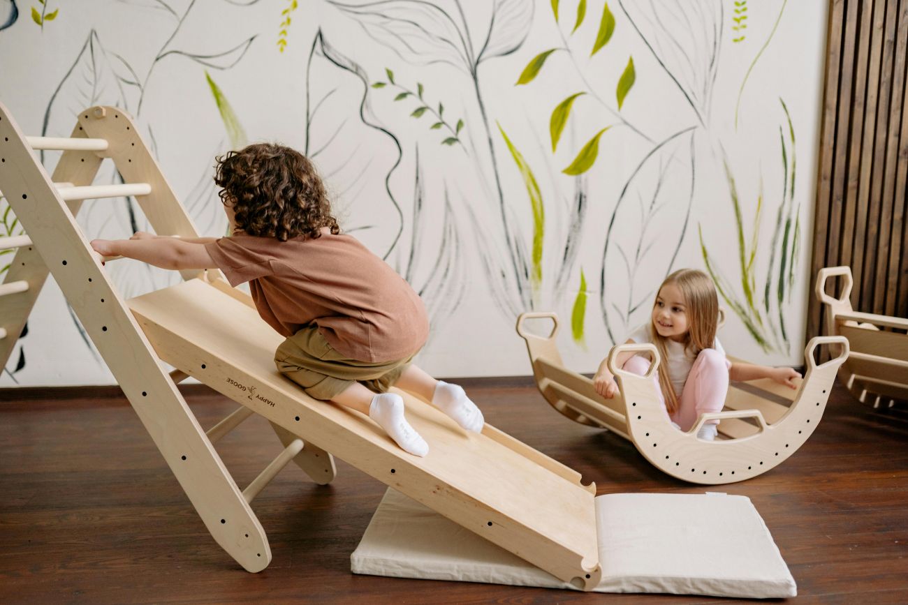 Kinder spielen mit Kletterspielzeugen. Ein Junge versucht sich hochzuziehen währen ein Mädchen ihm dabei zuschaut.  