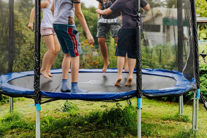 Kinder auf einem Trampolin. Man sieht nur ihre Unterkörper springen.