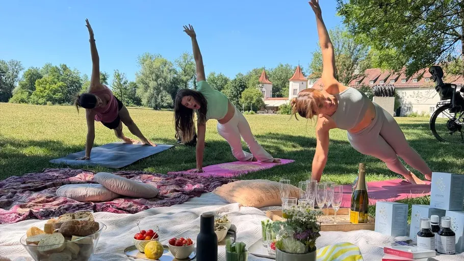 Yoga-Session beim Picknick auf einer Wiese.