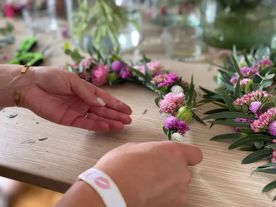 Zwei Hände binden einen Blumenring