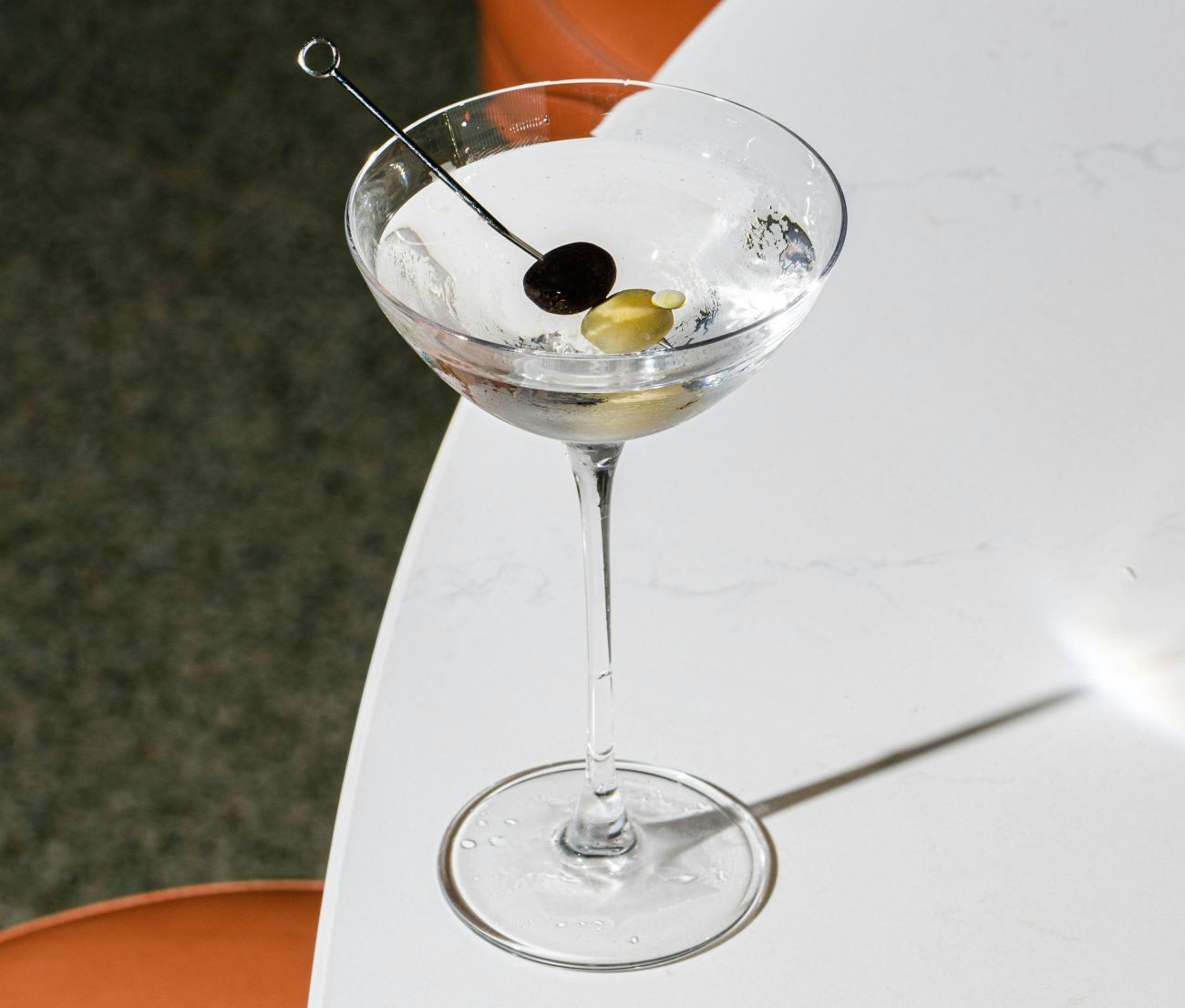 Ein Classic-Martini mit Oliven steht auf einem Tisch.
