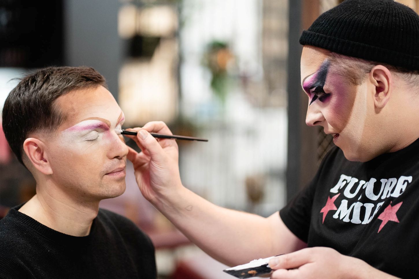 Einem Mann werden die Augen geschminkt.