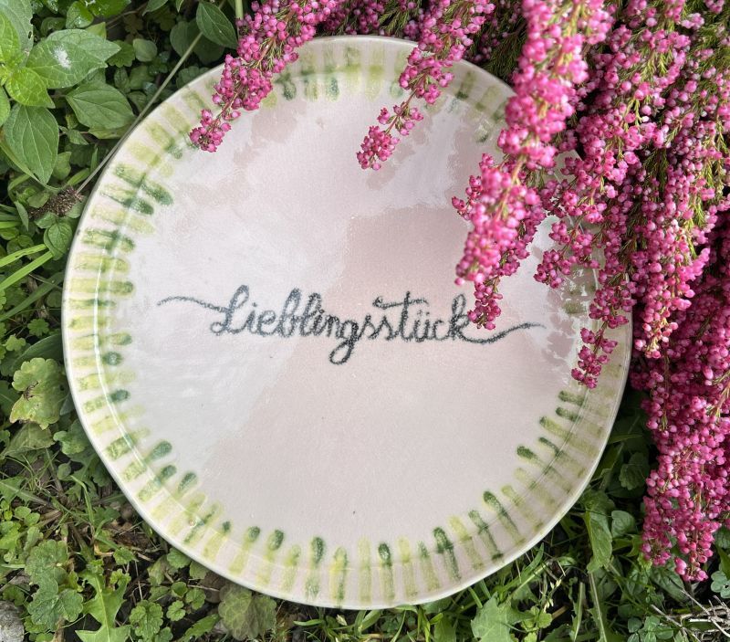 Keramik-Teller mit Schrift und Verzierung.