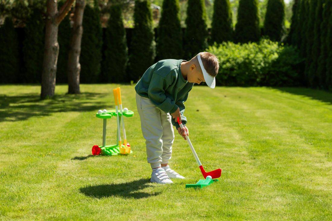 Ein Kind spielt Golf im Garten.