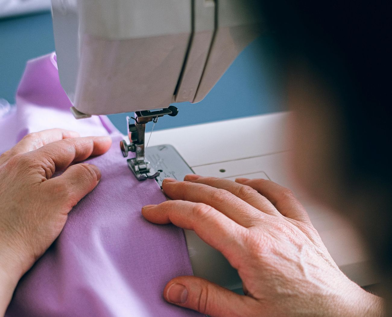 Eine Person näht an einer Nähmaschine.
