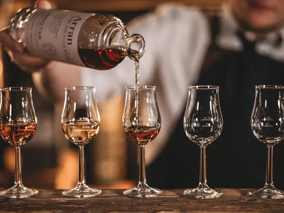 Jemand schenkt Rum in kleine Gläser ein