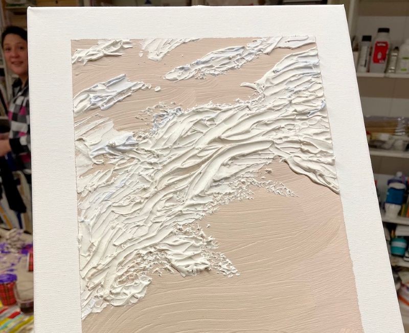 Weiße Strukturpaste auf einer Leinwand.