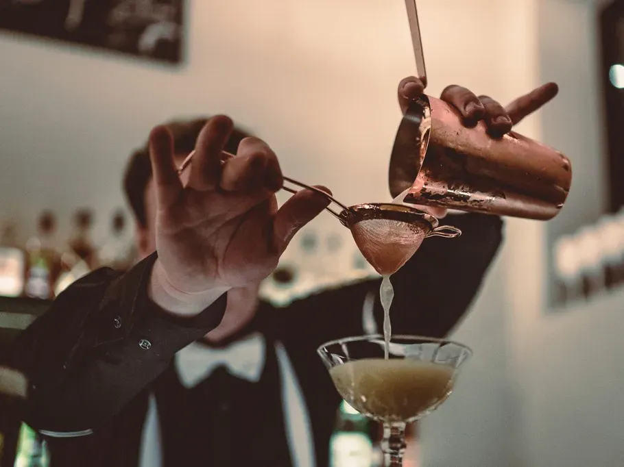Ein Barkeeper gießt eine Flüssigkeit durch einen Sieb