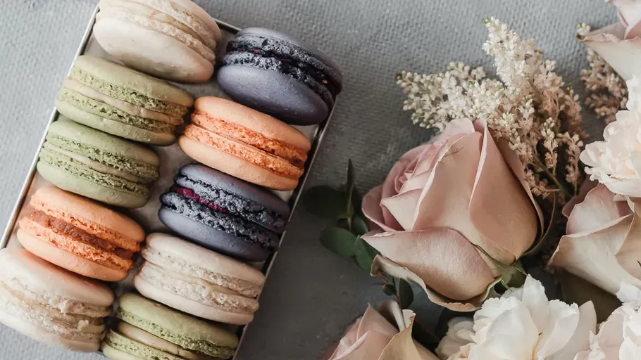 Macarons in einer Schachtel neben Rosen