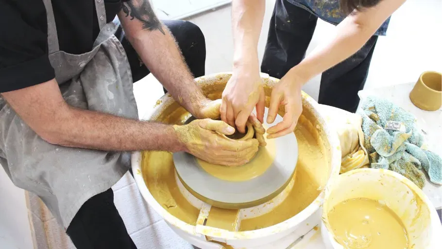 Zwei Menschen beim Töpfern an der Drehscheibe